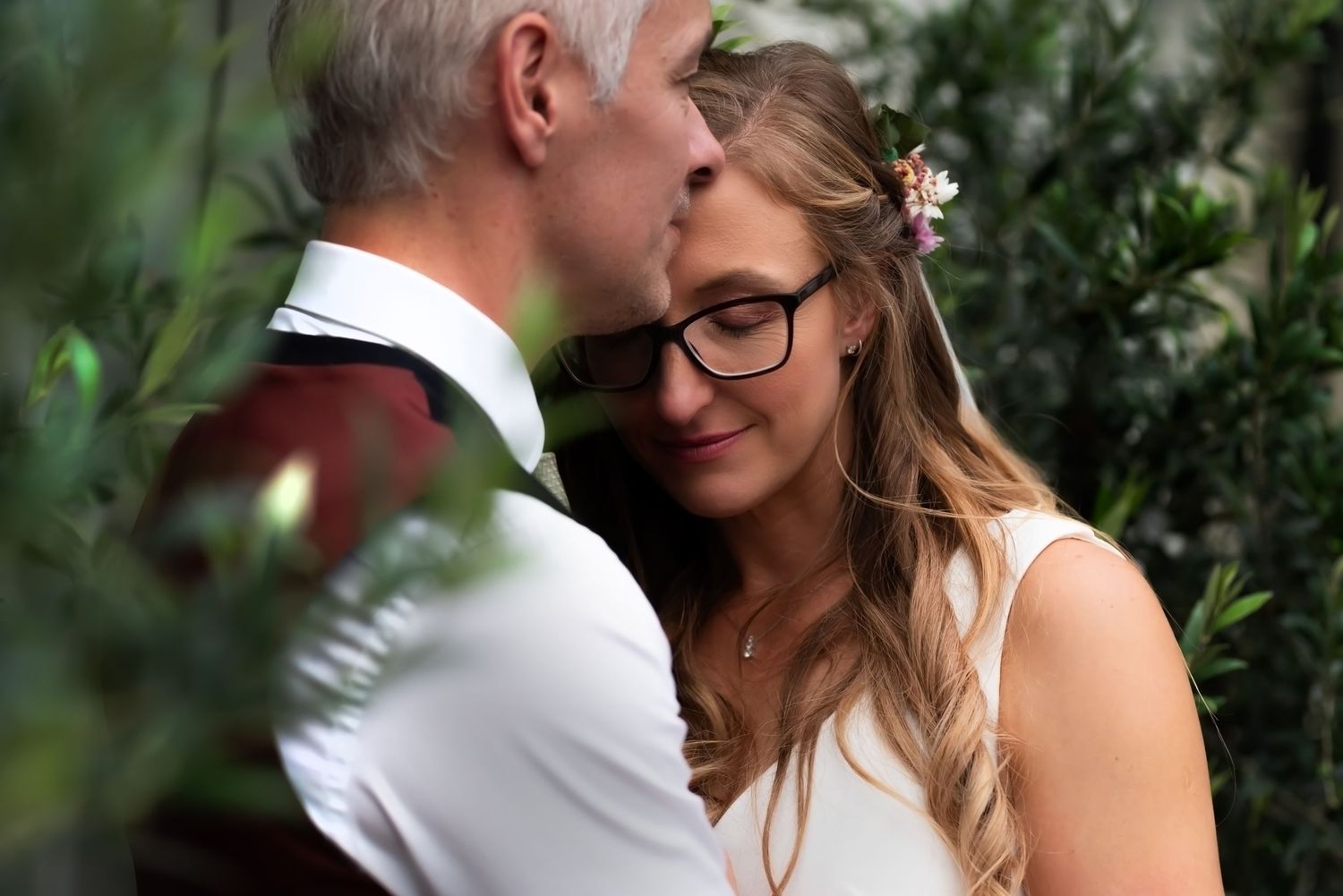 A tender moment between a couple captured during their wedding ceremony with autumn flowers in the background.