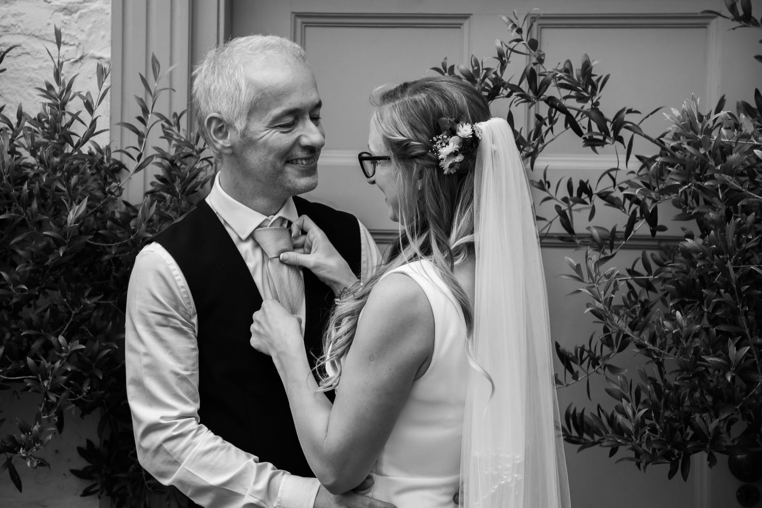 Black and white candid moment of couple sharing laughter outdoors.