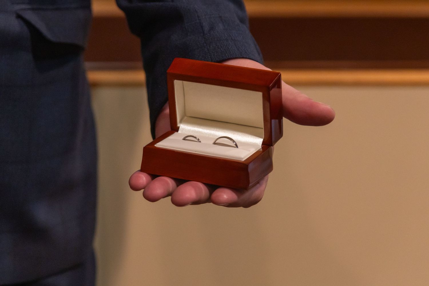 Close up of wooden ring box being opened during ceremony.