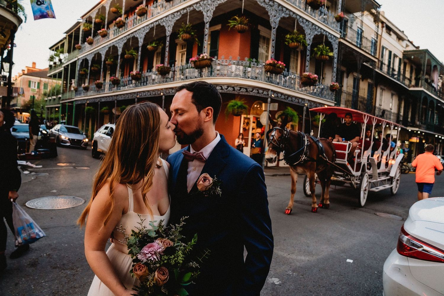 A newlywed couple kisses in from of the LaBranche House on Royal Street in New Orleans and a mule walks behind.