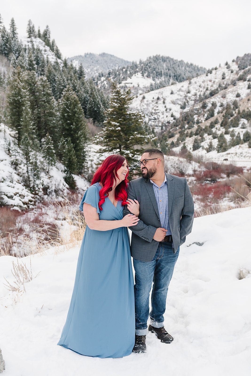 A couple shares an intimate moment against a snow-covered mountain backdrop.