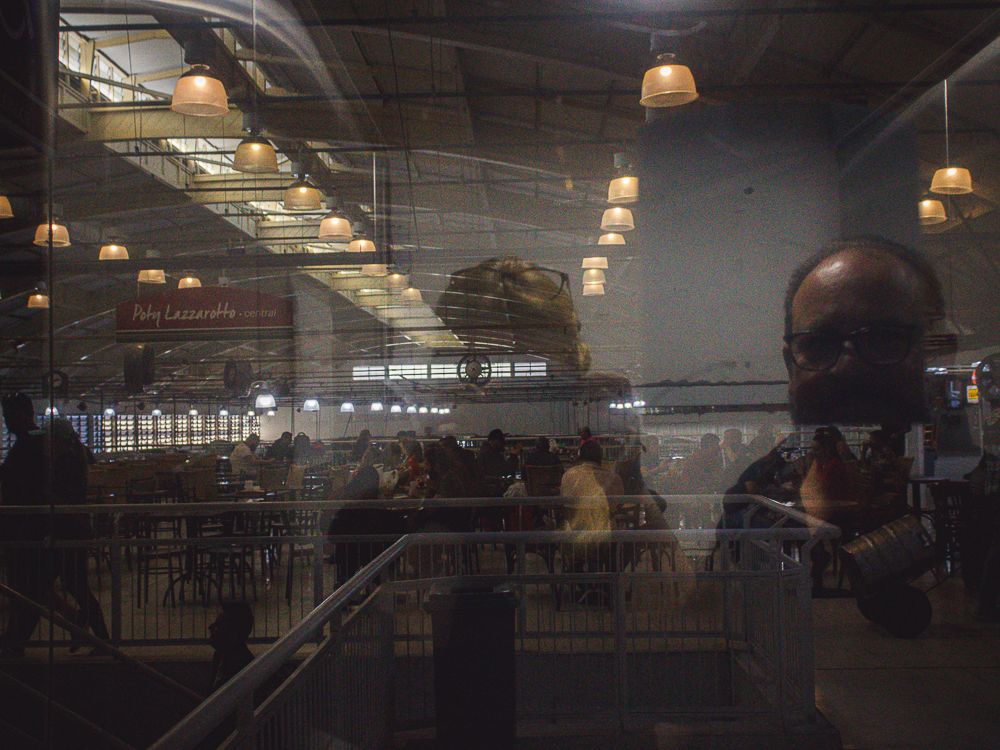 Interior market reflection with layered glass and warm lighting, photographed by Piret Victoria Ribas.