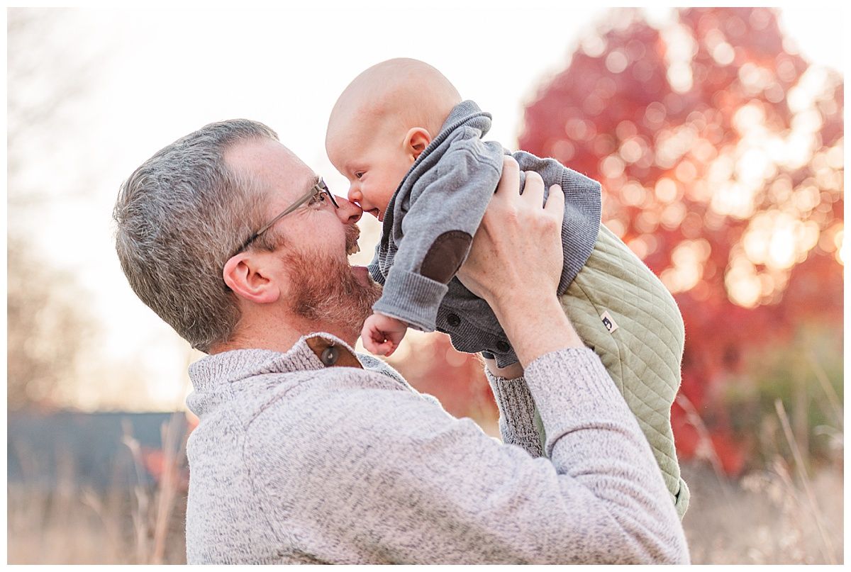 Sweet photo of father and baby son nose to nose with autumn colors in November at Starkey Park in Zionsville