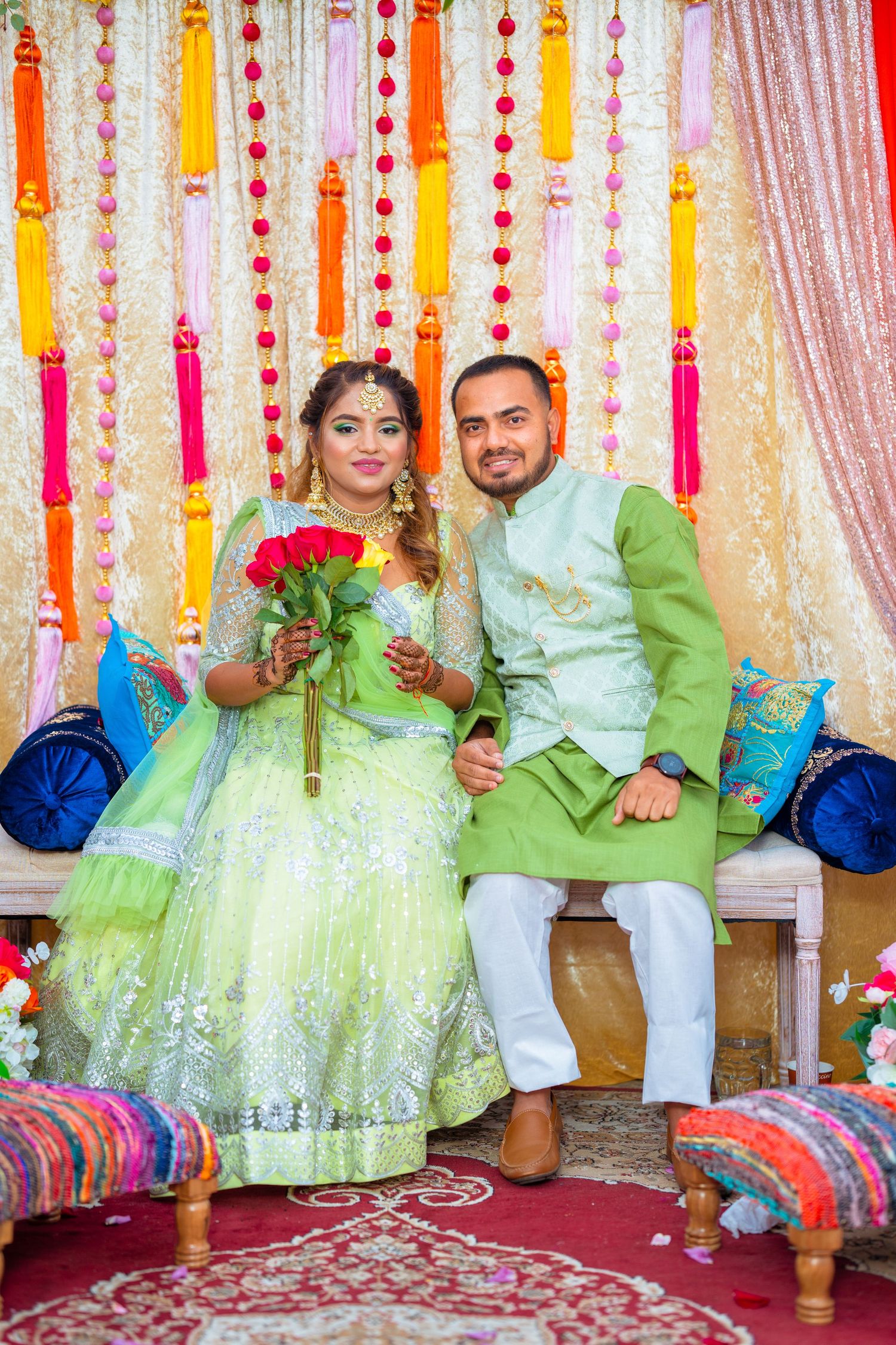 Happy couple in coordinating mint green and white outfits pose on decorated wedding stage.