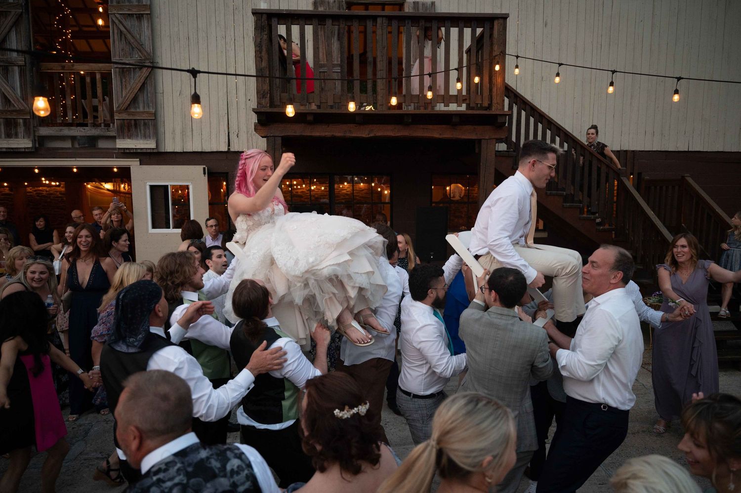 A bride being lifted by guests during a lively wedding dance celebration.