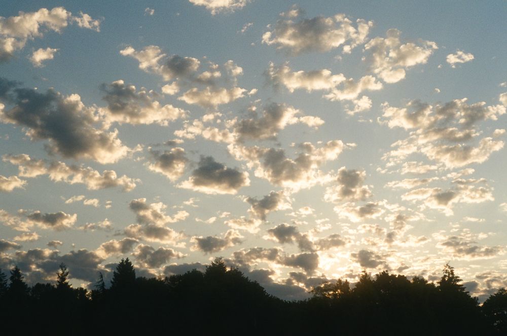 Dramatic sunset sky with golden clouds silhouetted against darkening mountain landscape.
