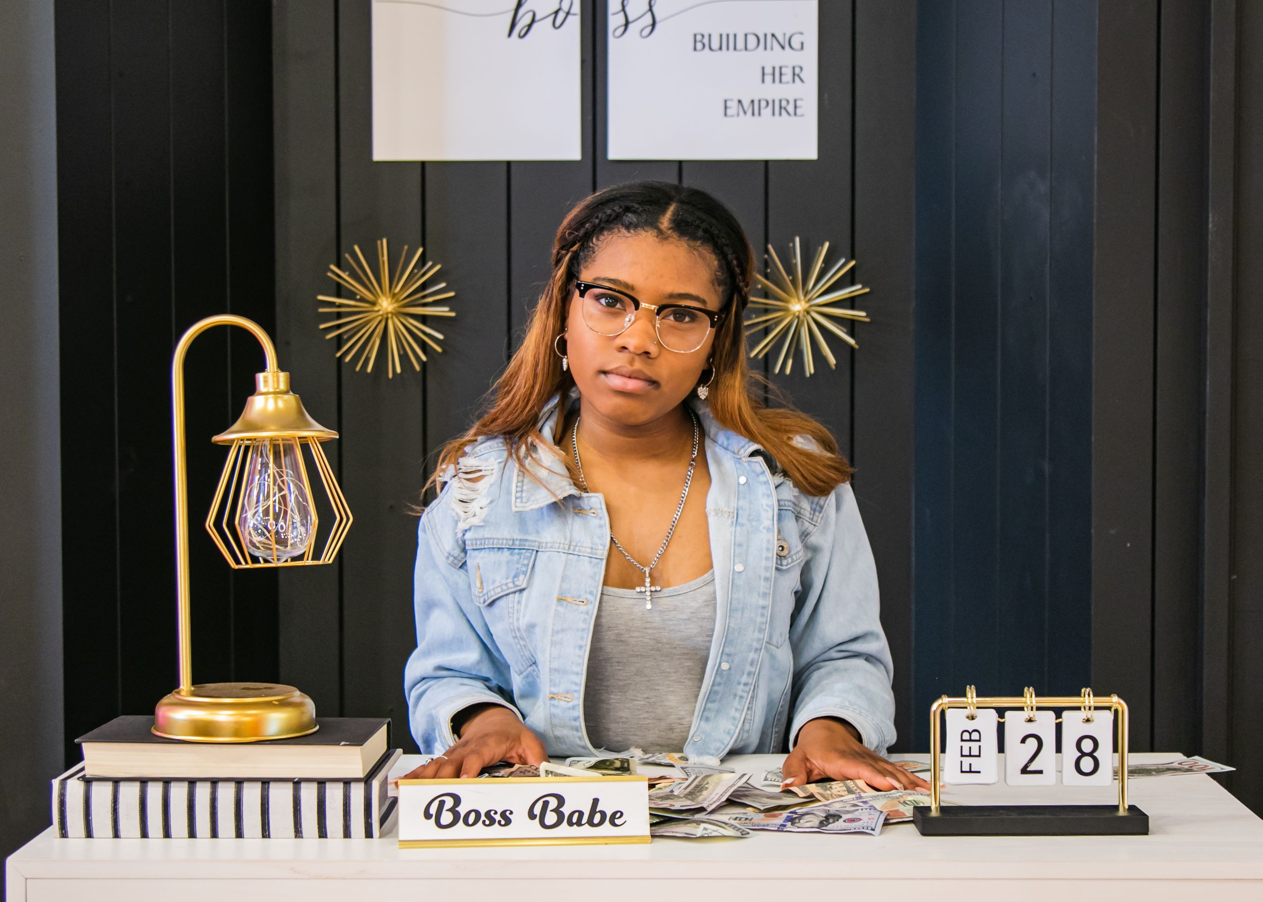 Professional desk setup with decorative lamp and name plate against dark wall with gold accents.
