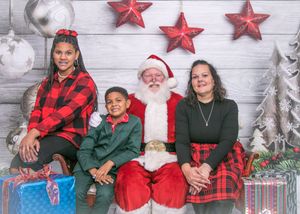 Family Christmas photo with Santa Claus surrounded by decorative stars and presents.
