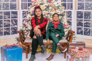 Holiday portrait with decorated Christmas tree, wrapped presents, and festive buffalo plaid outfits.