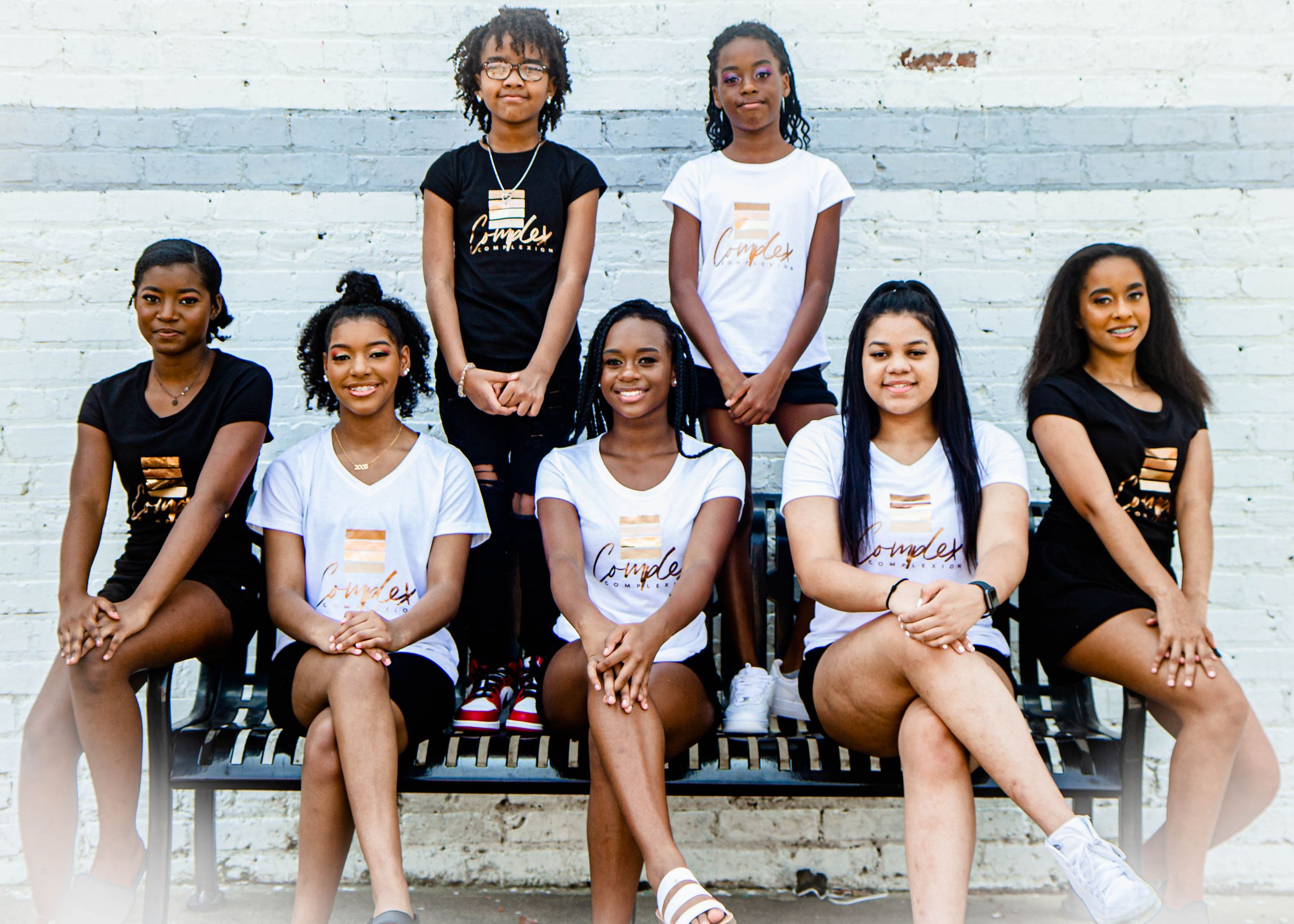 Group of young athletes in matching shirts sitting on bleachers outdoors.