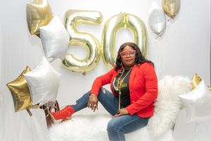 Birthday celebration setup with gold number 50 balloons and white star decorations against light background.