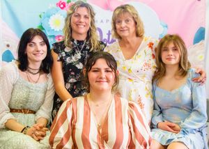 Group portrait against pink floral backdrop in springtime dresses and outfits.