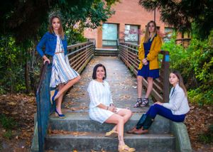 Group poses casually on outdoor wooden bridge steps in coordinated outfits.