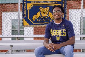 Student poses in front of NC A&T Aggies banner wearing university t-shirt.