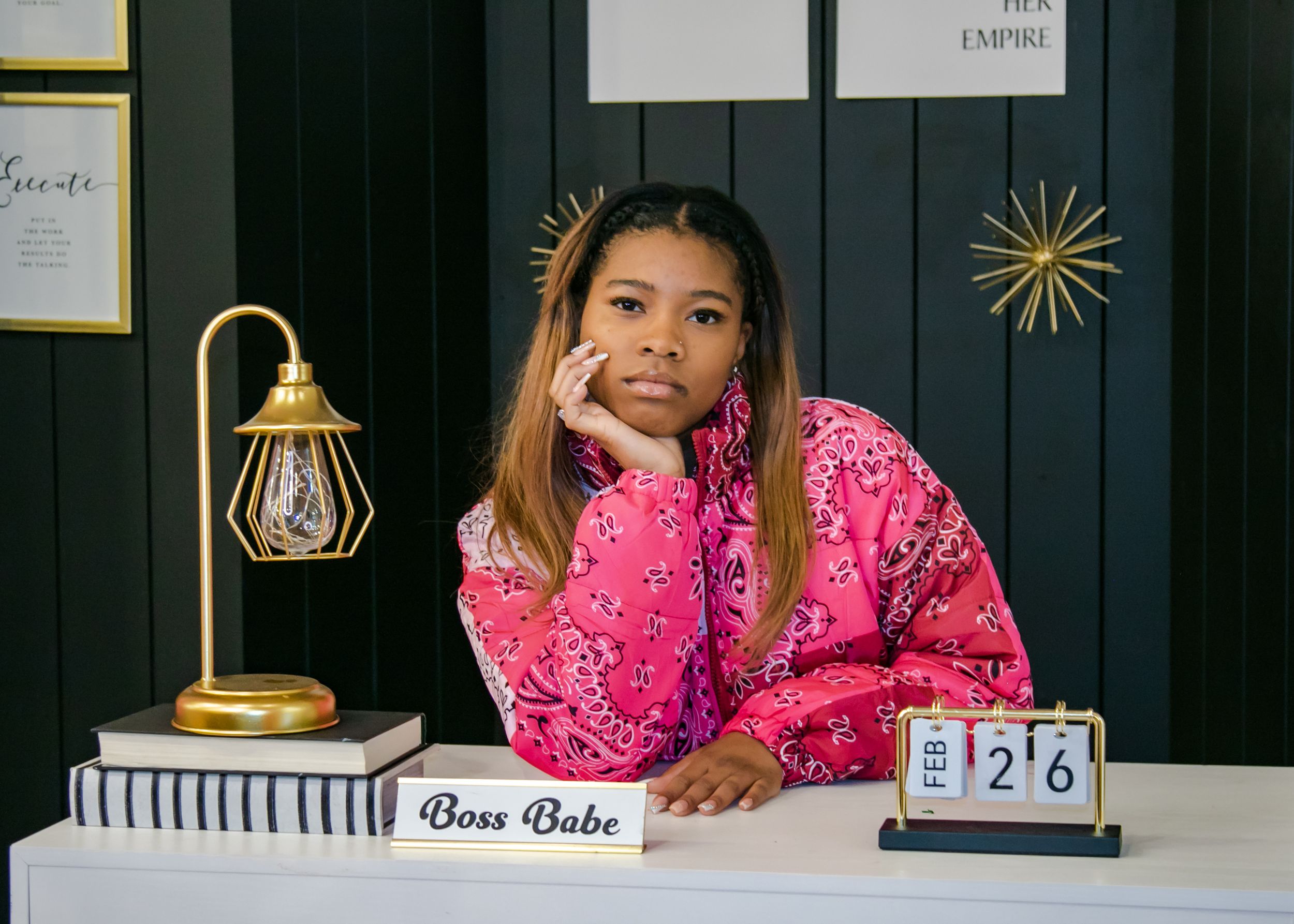 Office desk scene with gold lamp and calendar against dark wall with metallic star decorations.