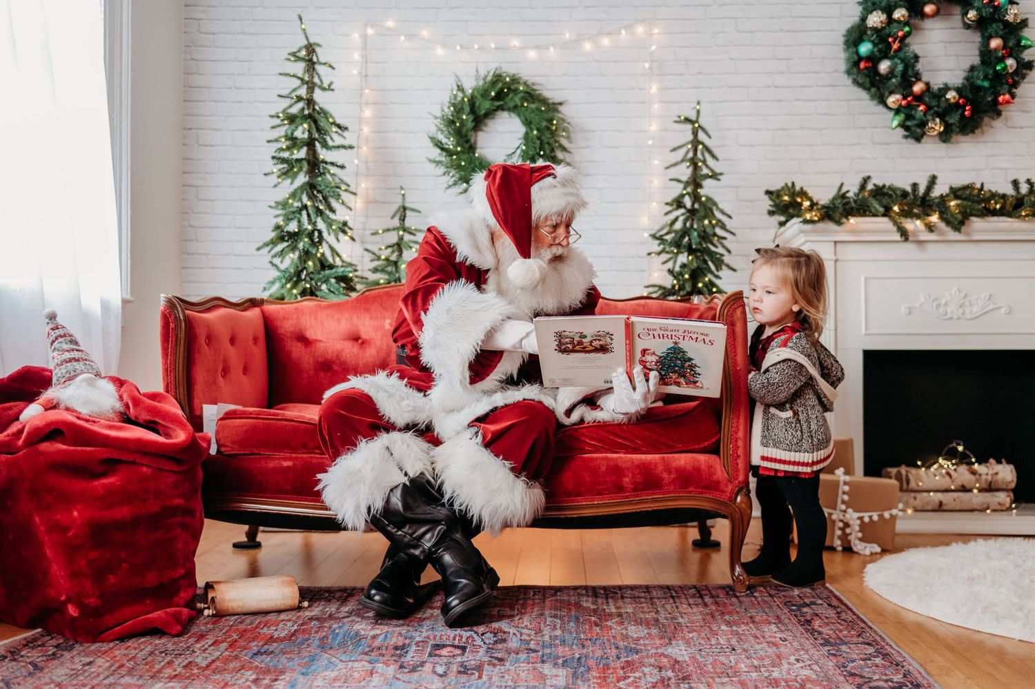 A festive Christmas scene with a red couch, decorated trees, wreaths, and twinkling lights in a cozy living room where Santa reads a story.