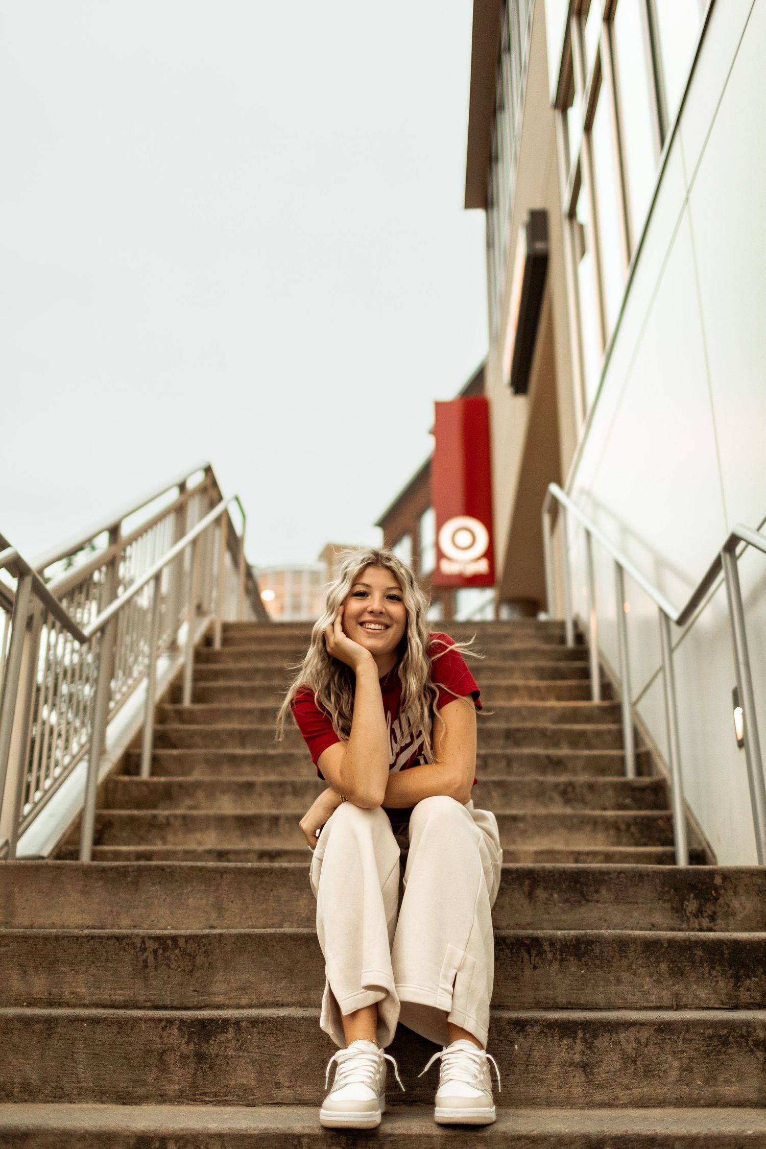 Person in red shirt sitting on concrete steps with joyful expression.