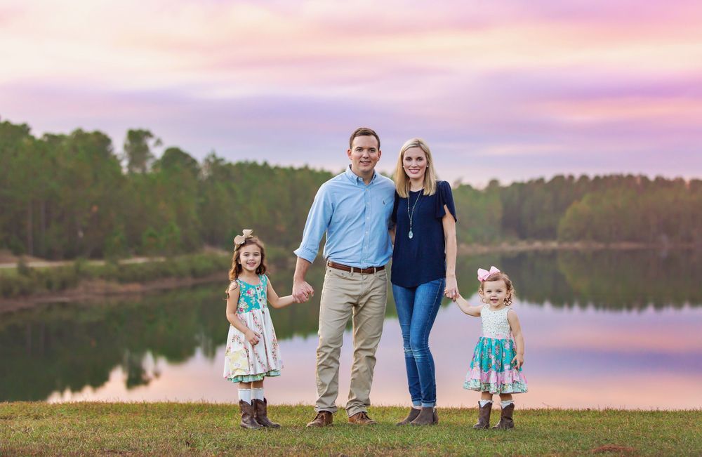 A series of sunset family photos taken near a tranquil lake with pink and purple sky.