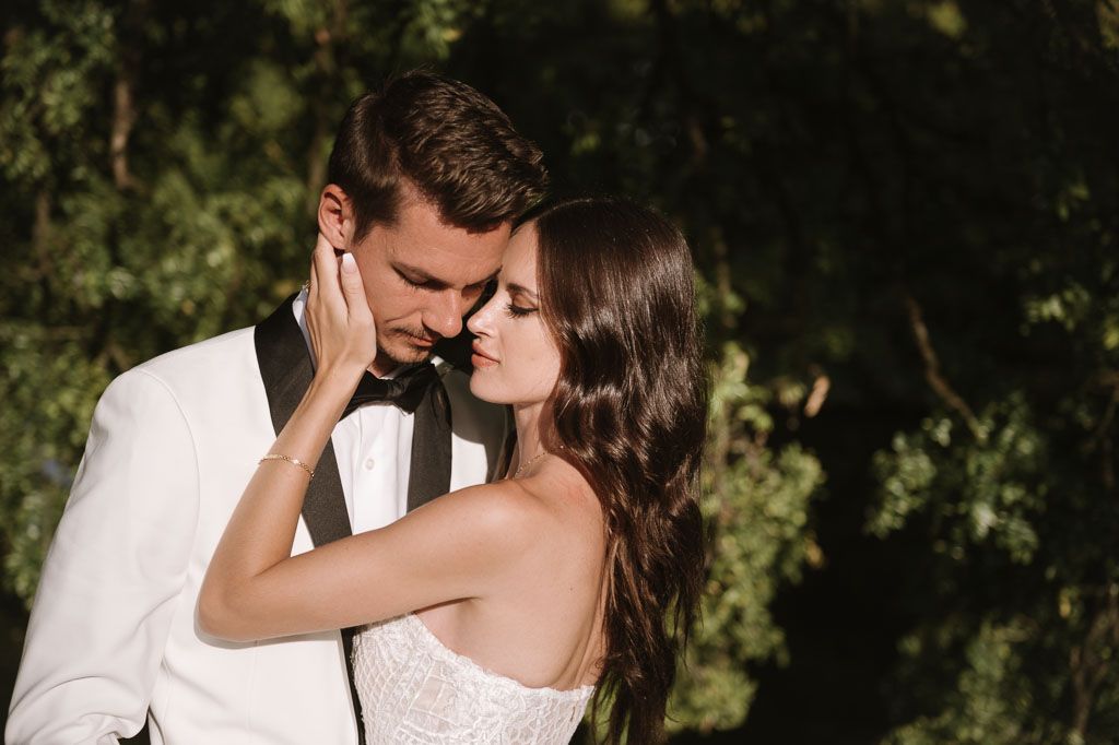 Intimate wedding portrait showing gentle embrace against garden backdrop.