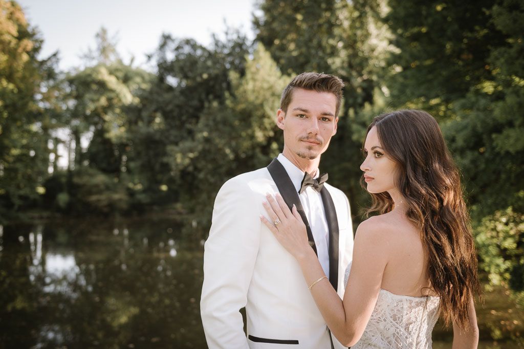Romantic wedding portrait of couple in white attire against natural garden backdrop.