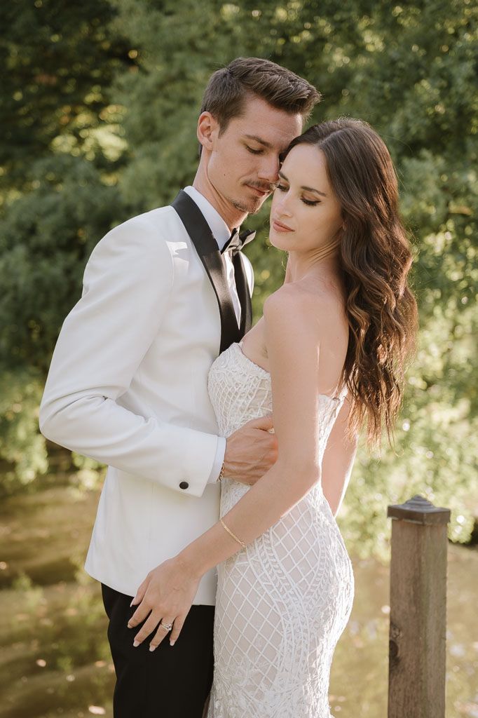 Tender embrace between couple in wedding attire during outdoor garden photoshoot.