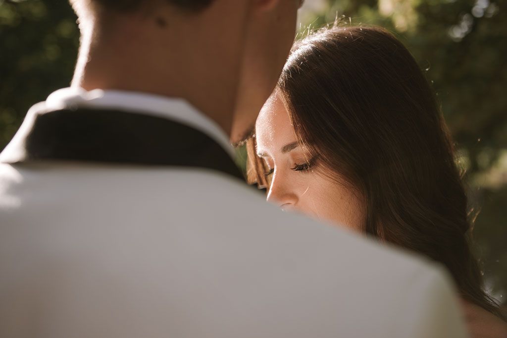 Intimate close-up of couple sharing tender moment during outdoor wedding photoshoot.