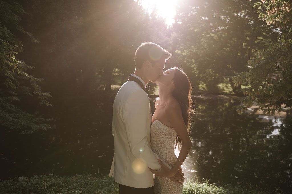 Dreamy backlit wedding portrait of couple embracing in golden sunset light.