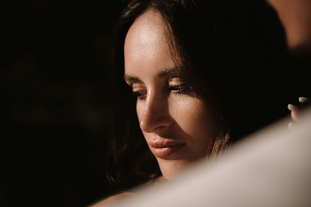 Artistic close-up portrait of bride in warm, dramatic lighting.