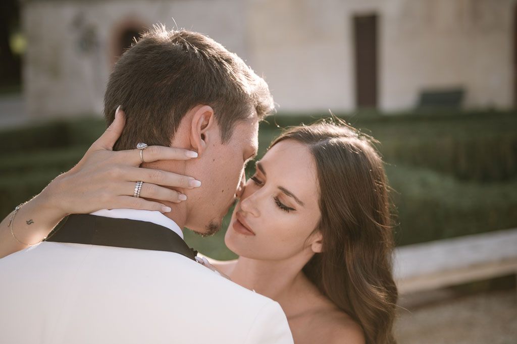 Intimate wedding portrait showing tender embrace against garden backdrop.