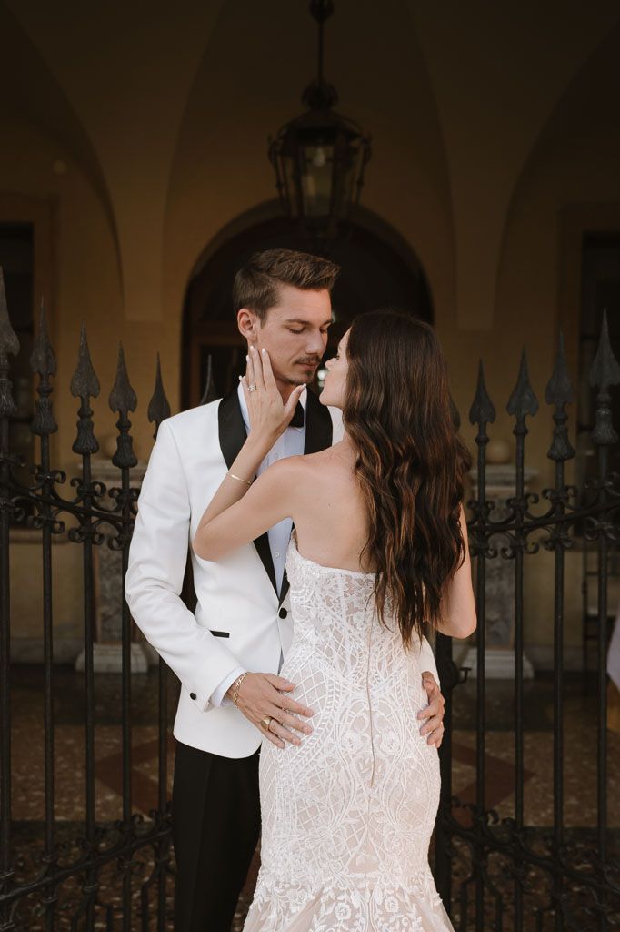 Romantic moment between couple against ornate iron gates and stone architecture.