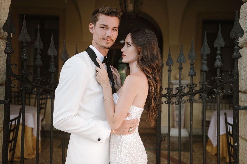 Bride and groom share an intimate moment in formal attire against a classic architectural backdrop.