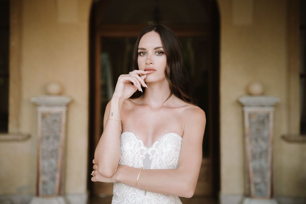 A thoughtful bridal pose captured against classic architecture with stone columns.
