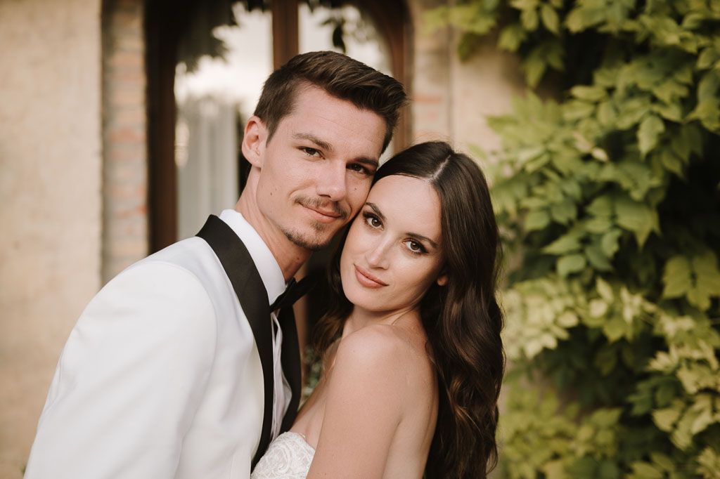 A romantic wedding portrait captured outdoors with ivy-covered walls in the background.