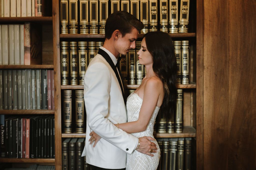 A romantic moment captured in a library setting with vintage books as the backdrop.