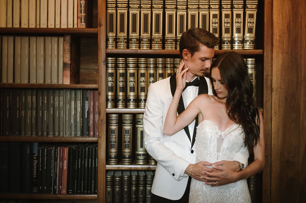 An intimate wedding portrait in a classic library with wall-to-wall bookshelves.