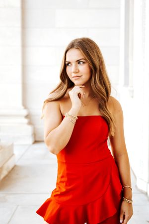 Indoor portrait session featuring a vibrant red dress against a bright white background.