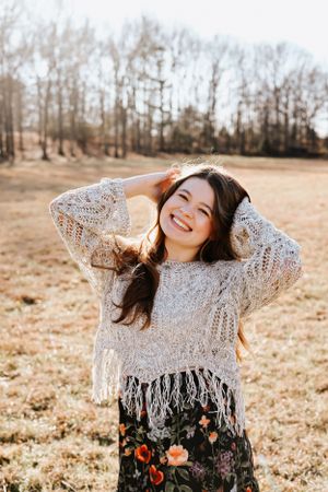 Joyful outdoor photoshoot featuring a cream lace top with fringe details in a natural setting.