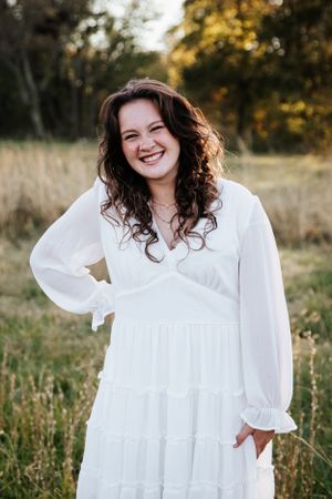A series of outdoor portraits showing someone in a white flowing dress with ruffles in a sunlit field.