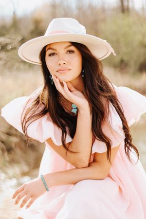 Sun-kissed portrait series featuring delicate pink fashion and a statement hat.