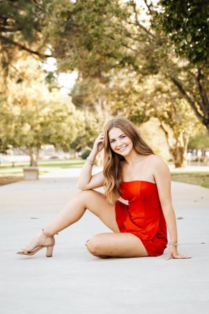 Artistic outdoor photo series with a red dress on a sunlit path.