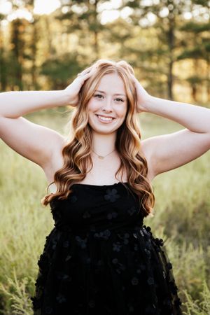 Natural light portraits with hands raised in graceful poses wearing a black textured dress.