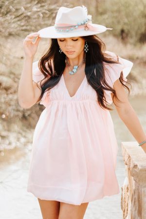 Dreamy summer photoshoot featuring a flowing pink top and wide-brimmed hat.