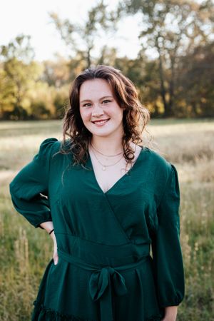 A series of outdoor portraits featuring someone in an emerald green wrap dress against a natural field backdrop.