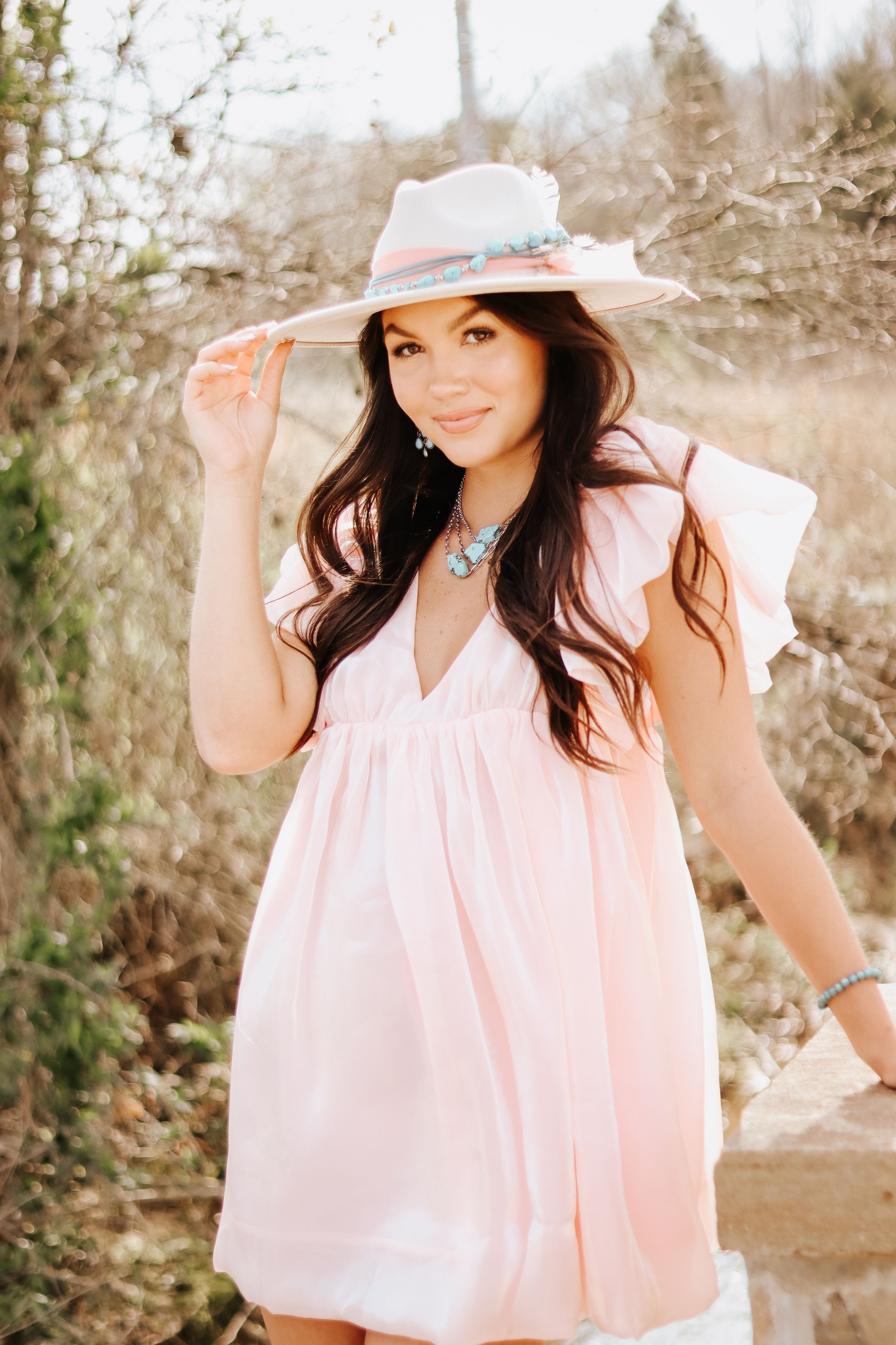 Soft sepia tones highlight a romantic portrait session with pink clothing and a sun hat.