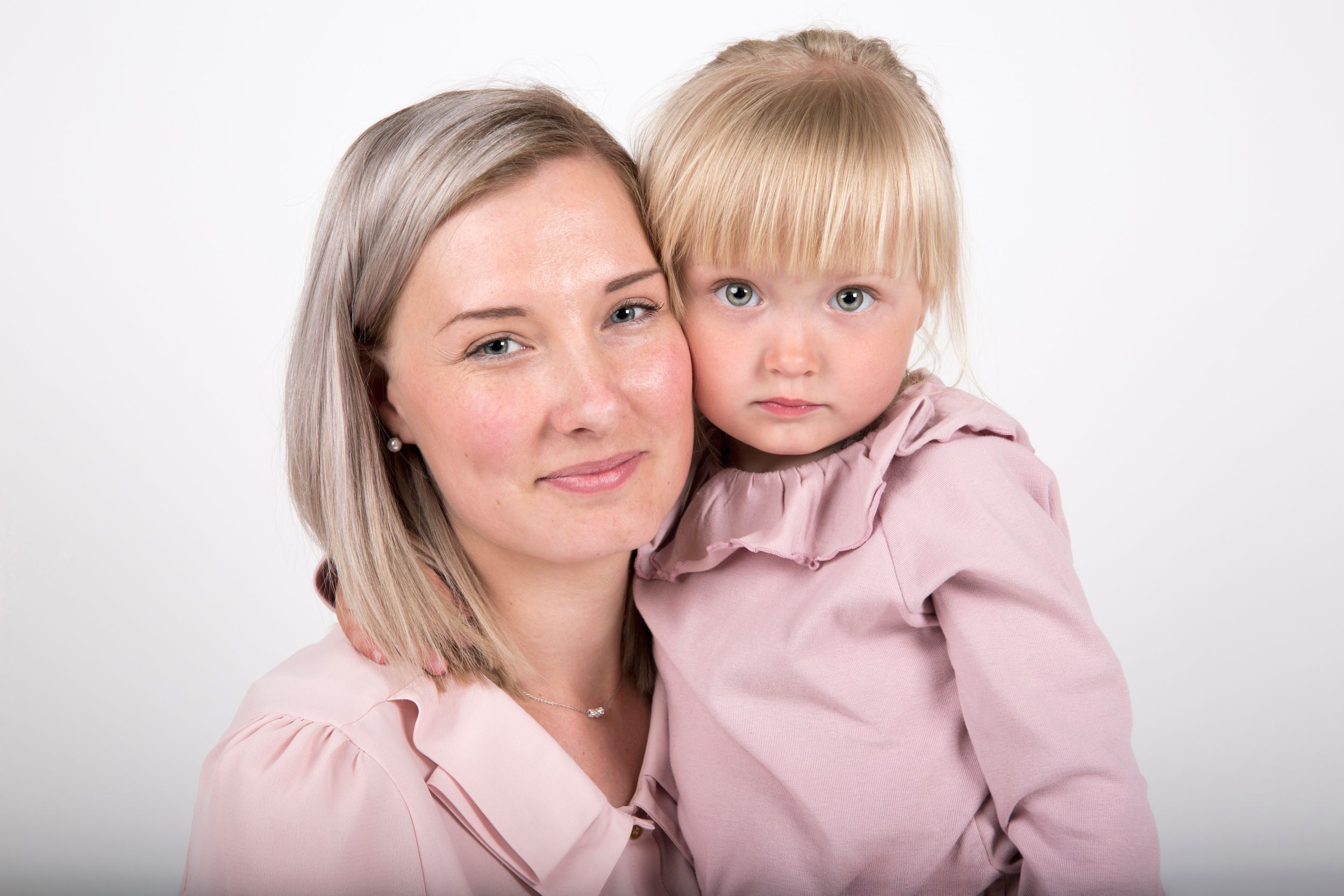 A sweet studio portrait showing matching pink outfits and tender expressions.