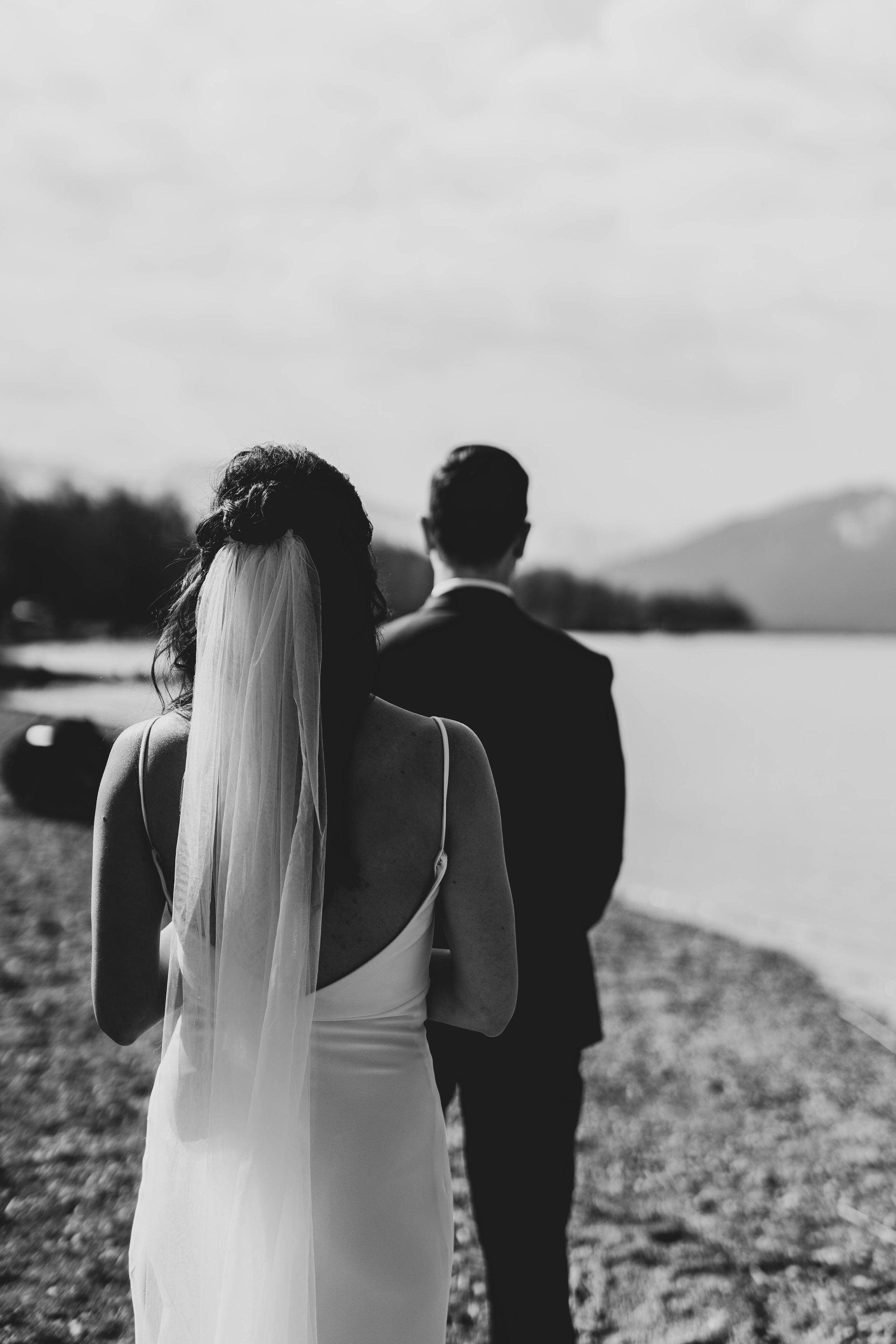 Scenic waterfront wedding moment with mountains in the background.