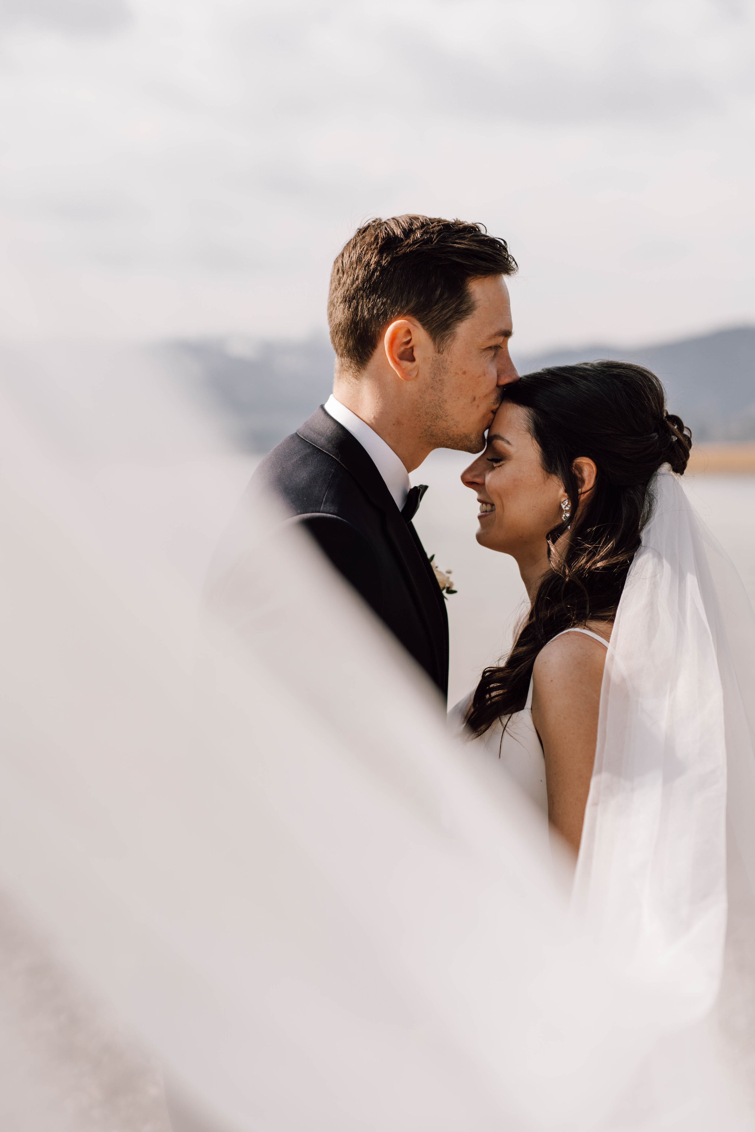 Intimate wedding moment captured against a cloudy mountain backdrop.