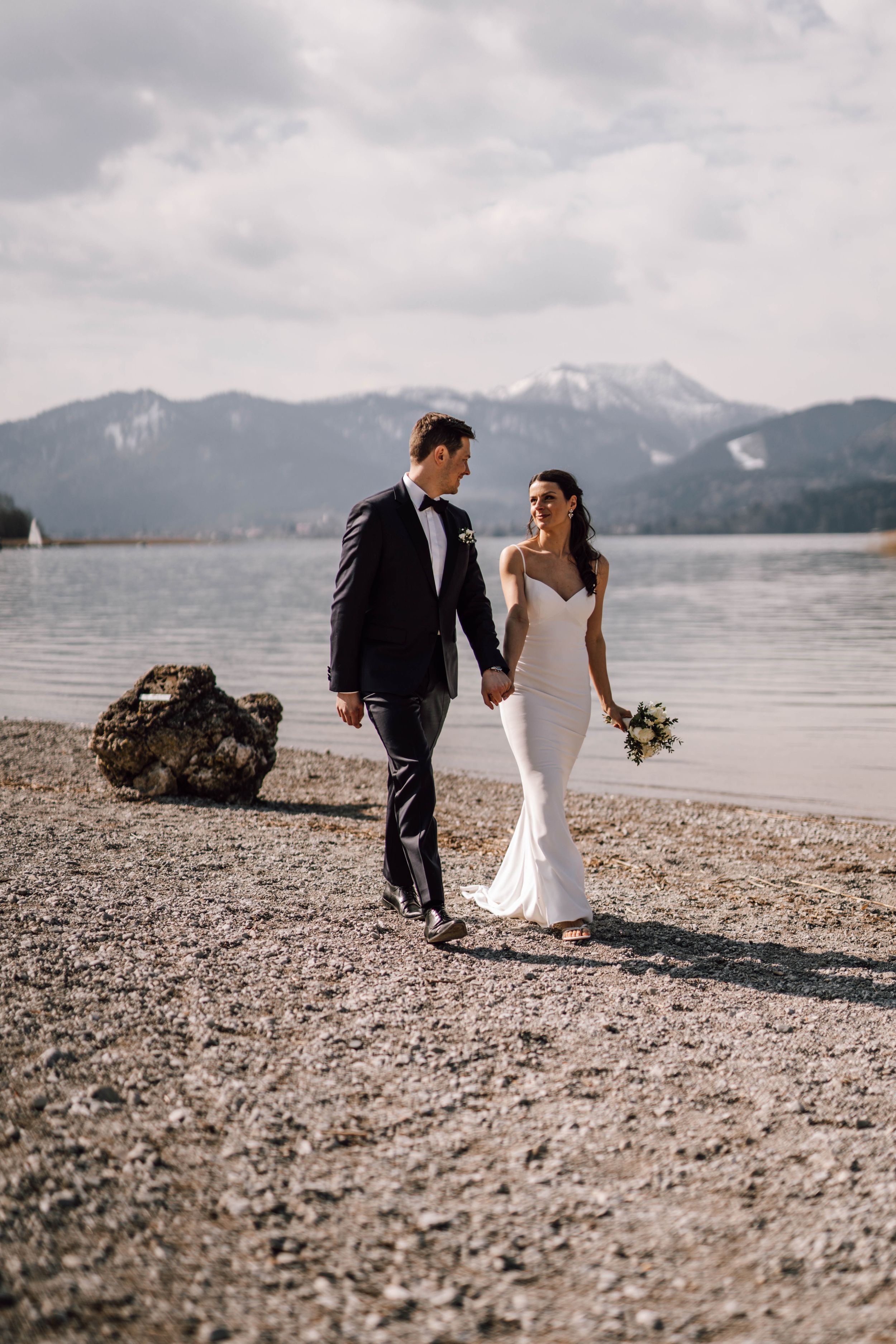 Scenic wedding photos on a beach with snow-capped mountains in the distance.