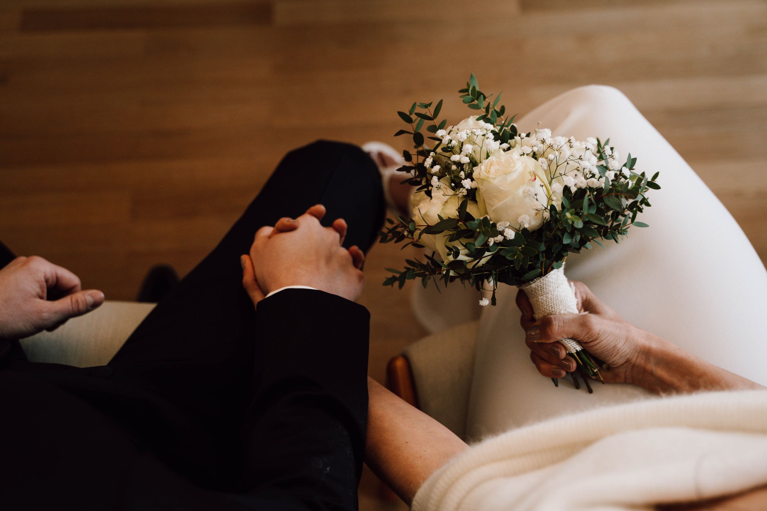 Close-up details of wedding flowers and decor against a wooden surface.