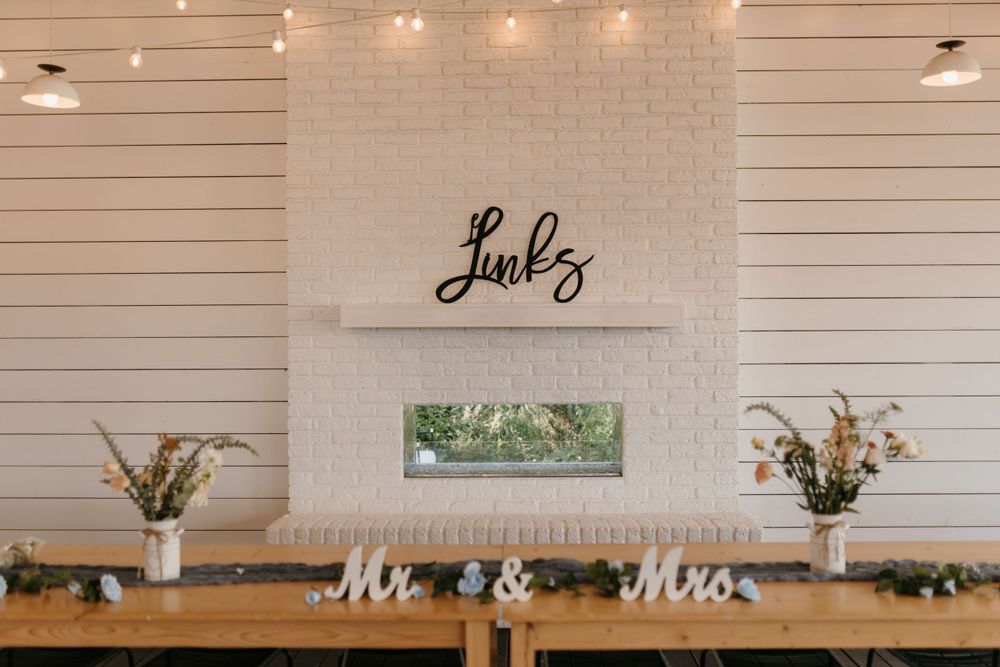 Wedding reception head table with Mr and Mrs signs beneath a fireplace with Links surname sign.
